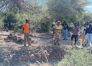 Godfrey Mutakura (orange t-shirt) and Queen Chimwoyo (wearing hat) show the graves that were about to be engulfed by one of the gullies they rehabilitated. 